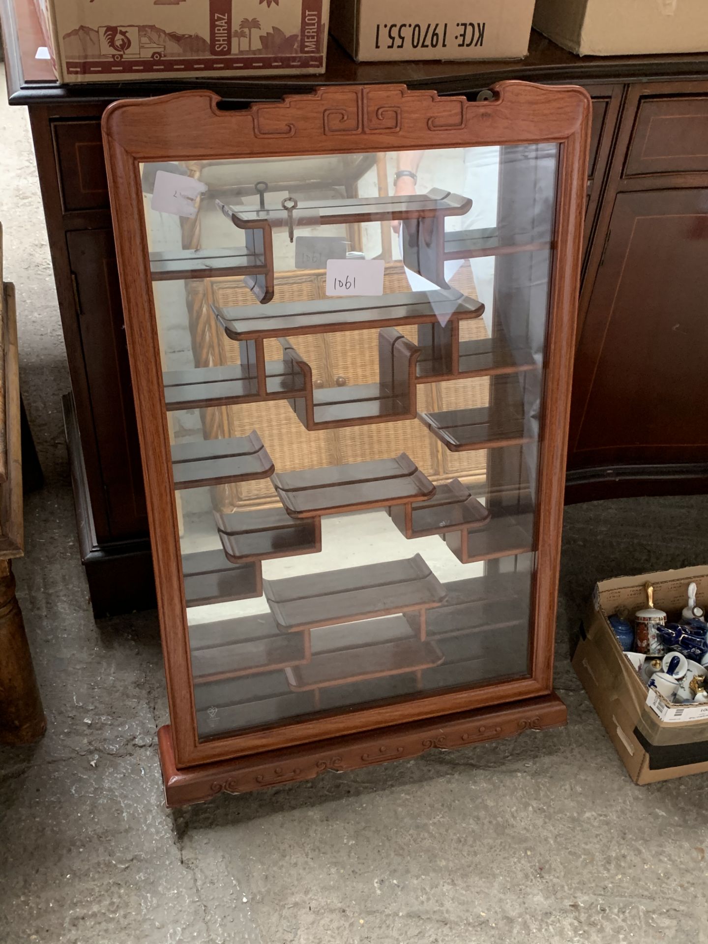 Chinese wall mounted display cabinet with key, together with a collection of ceramic bells.