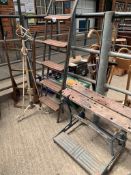 A work bench, set of metal steps, metal sack truck and a wrought iron oil lamp stand.