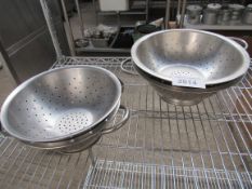 Four stainless steel colanders.