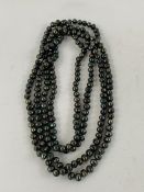 Large single string of individually knotted Tahitian black pearls.