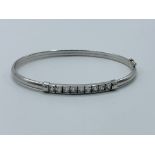 9ct white gold bangle with safety catch set with clear stones.