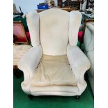 A large beige upholstered Victorian armchair on casters. 92 x 90 x 110cms.