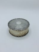 Circular silver trinket box with engine turned decorative top.