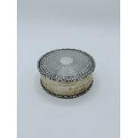 Circular silver trinket box with engine turned decorative top.