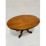 Mahogany oval tilt top table on carved pedestal to four feet.