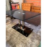 Black glass top table on twin chrome pedestal.
