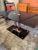 Black glass top table on twin chrome pedestal.