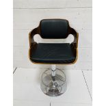 Black leather upholstered height adjustable swivel bar chair on chrome pedestal.