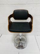 Black leather upholstered height adjustable swivel bar chair on chrome pedestal.