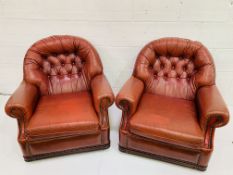 Pair of button back red leather arm chairs with studded trim to arms and back.