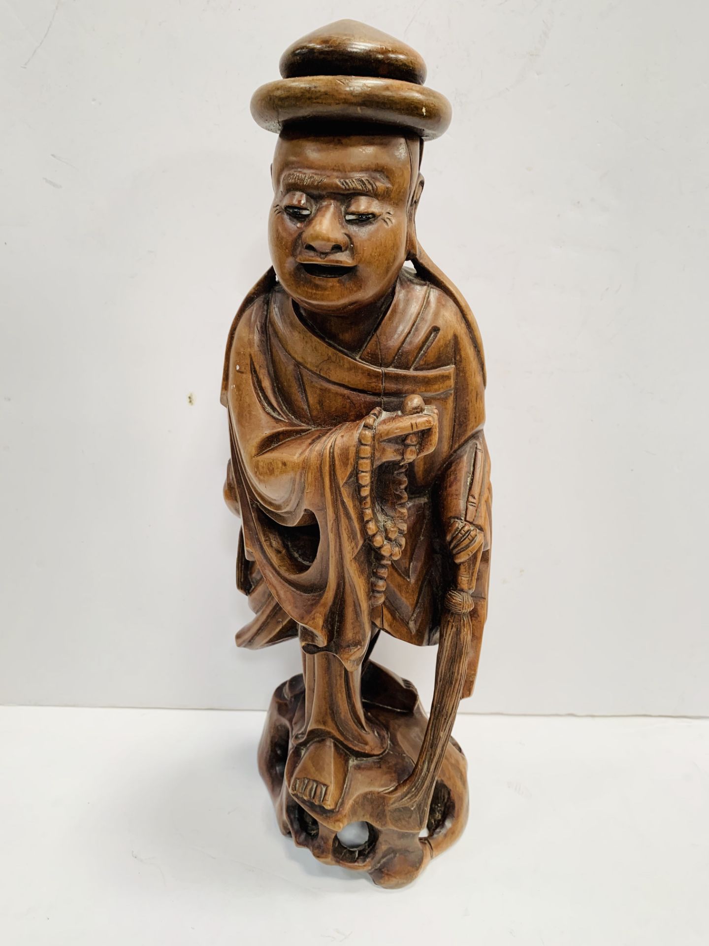 A wooden carved oriental figurine of a monk.