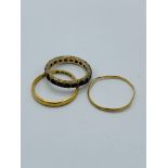 22ct gold band, a yellow metal band and a yellow metal and garnet eternity ring