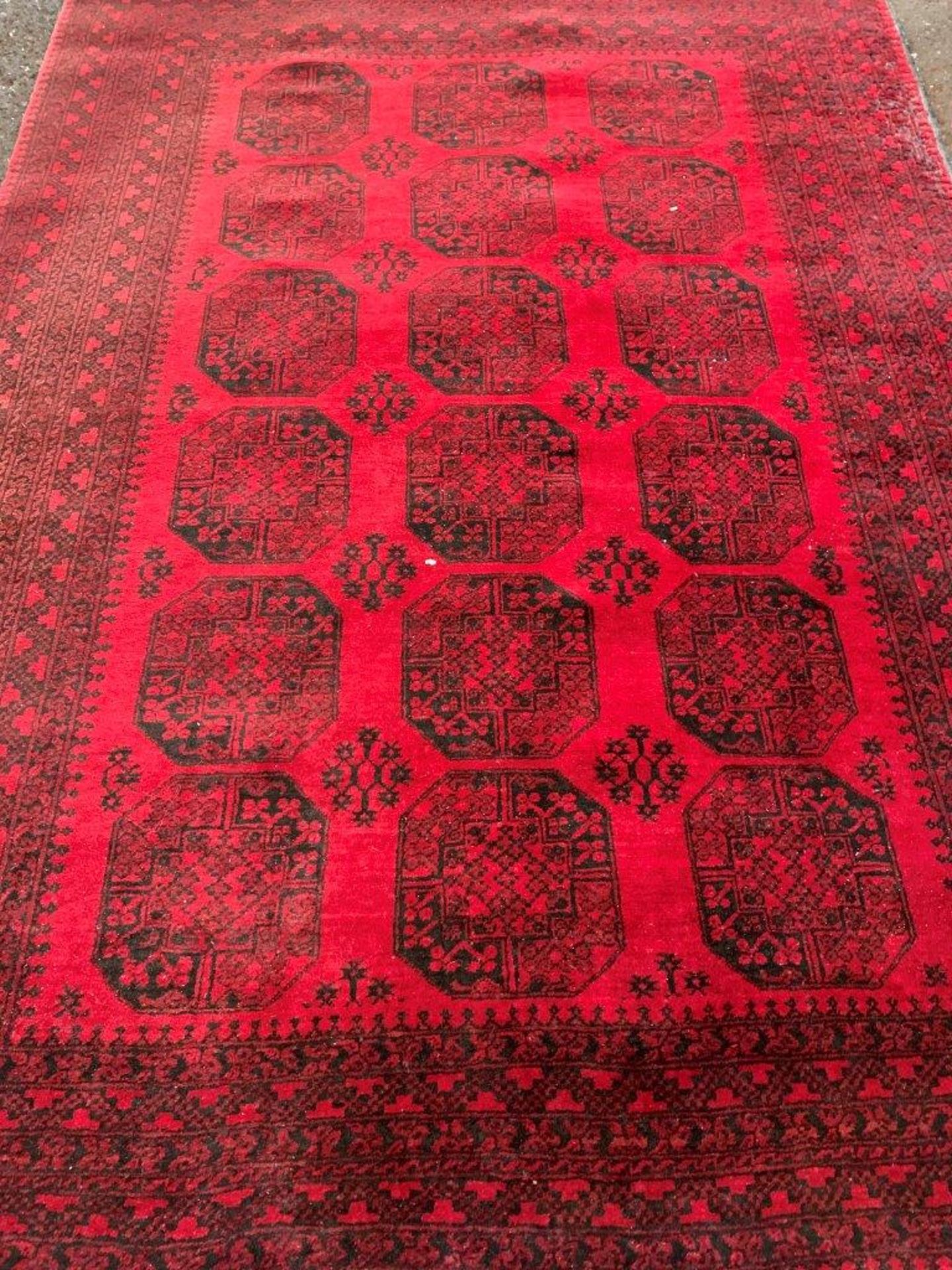 Wool pile red ground carpet rug made in Afghanistan.