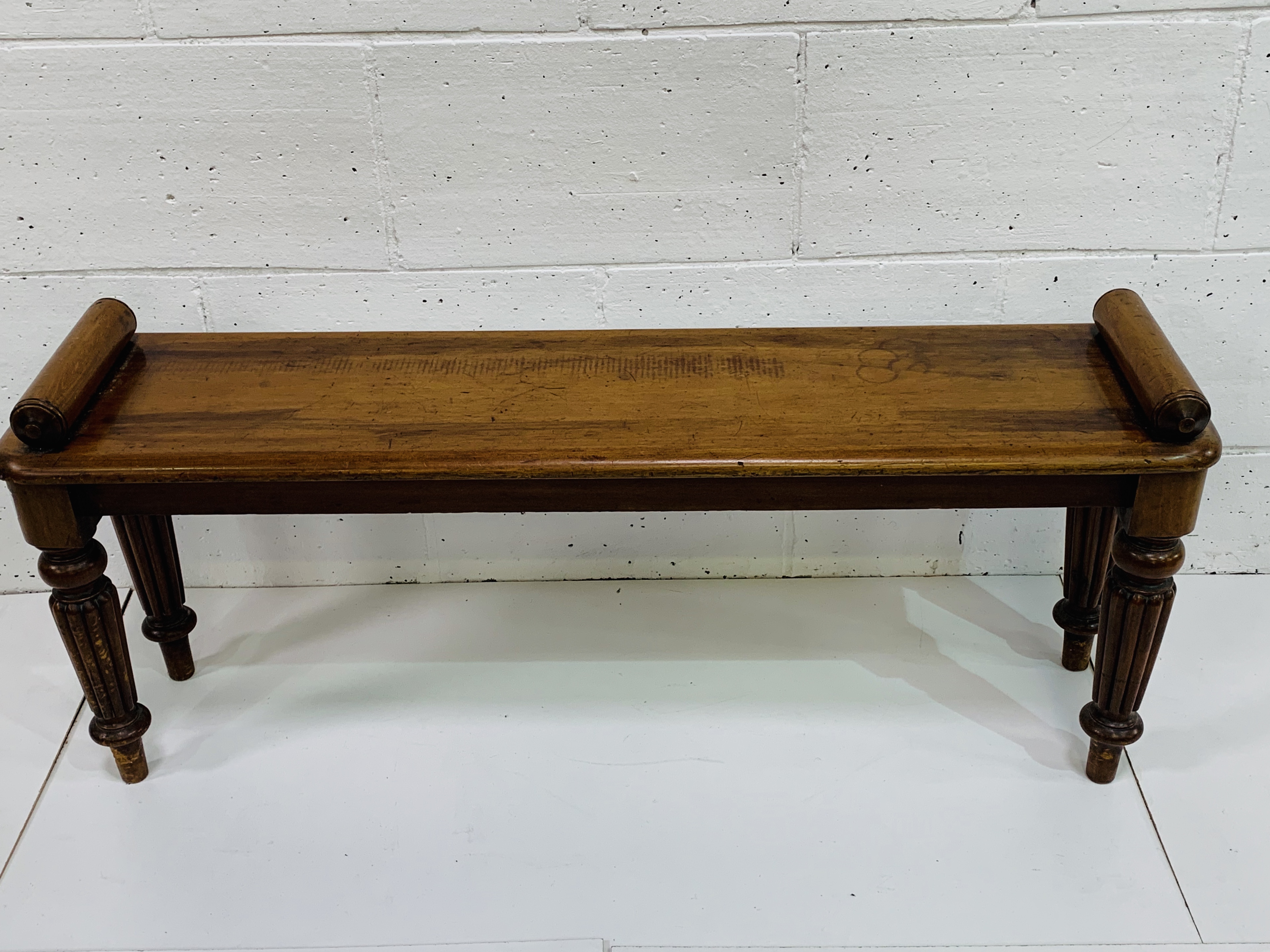 Mahogany hall bench with rolled ends on fluted legs.