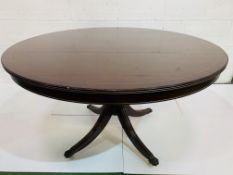 Mahogany circular tilt top table on central pedestal to four feet with casters.
