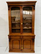 A Victorian fiddle back mahogany glazed bookcase over a frieze drawer beneath.