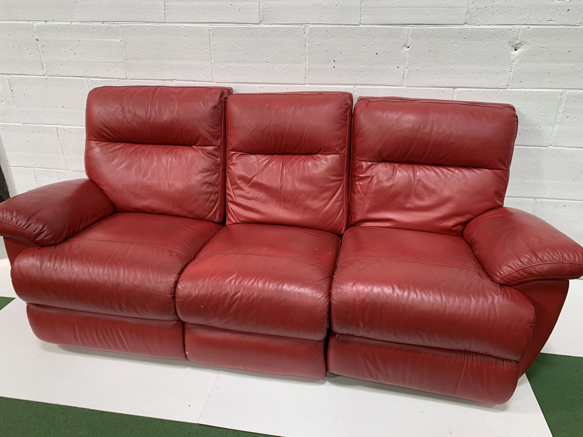 Red leather three seat sofa with reclining ends, and a matching pouffe.