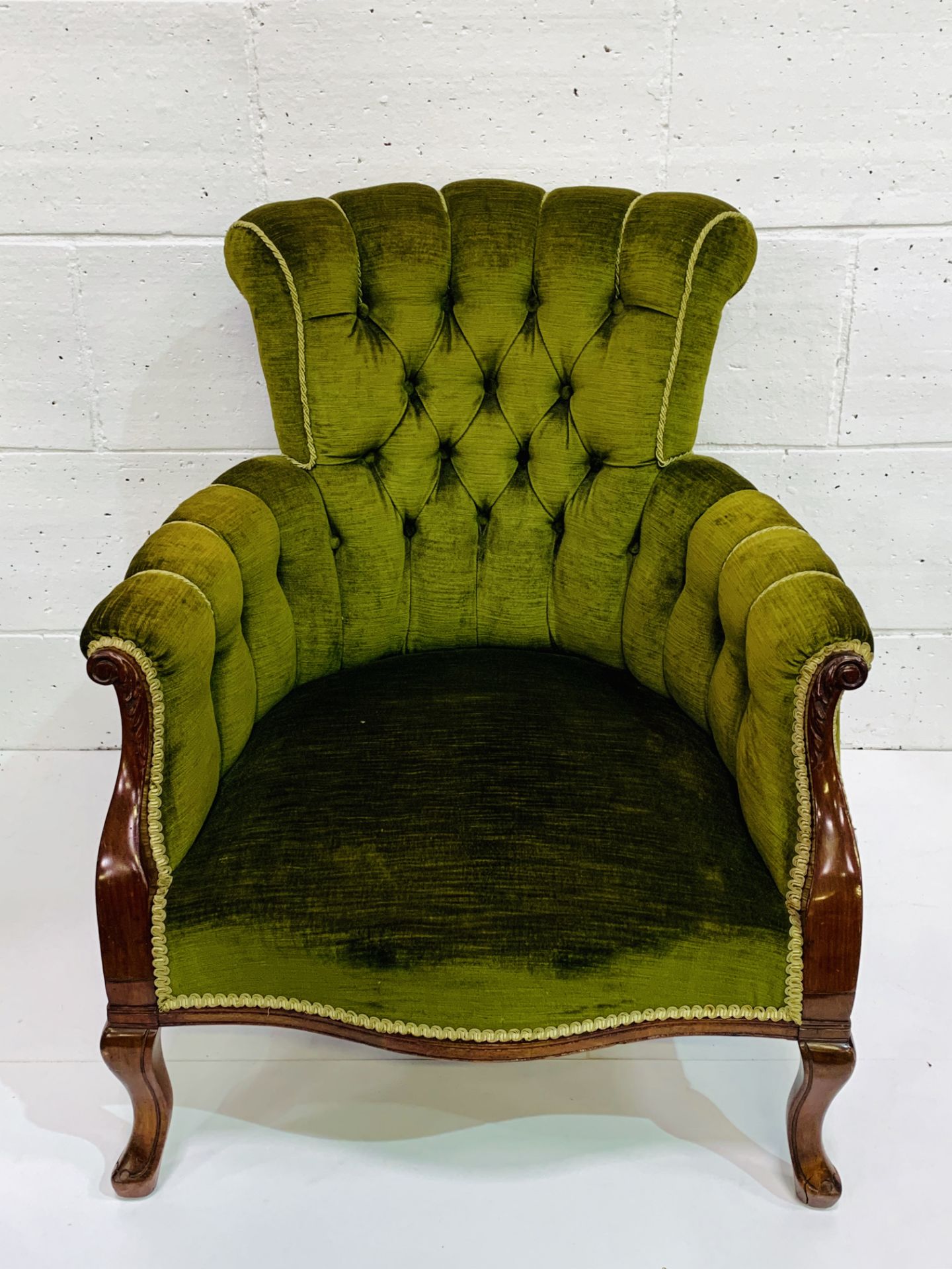 Drawing room chair upholstered in button back green upholstery.