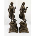 Two bronzed spelter female figurines as clock garnitures.