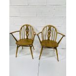 Two Ercol style rail back open armchairs, with carving to centre splat.