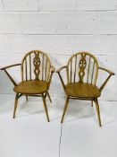 Two Ercol style rail back open armchairs, with carving to centre splat.