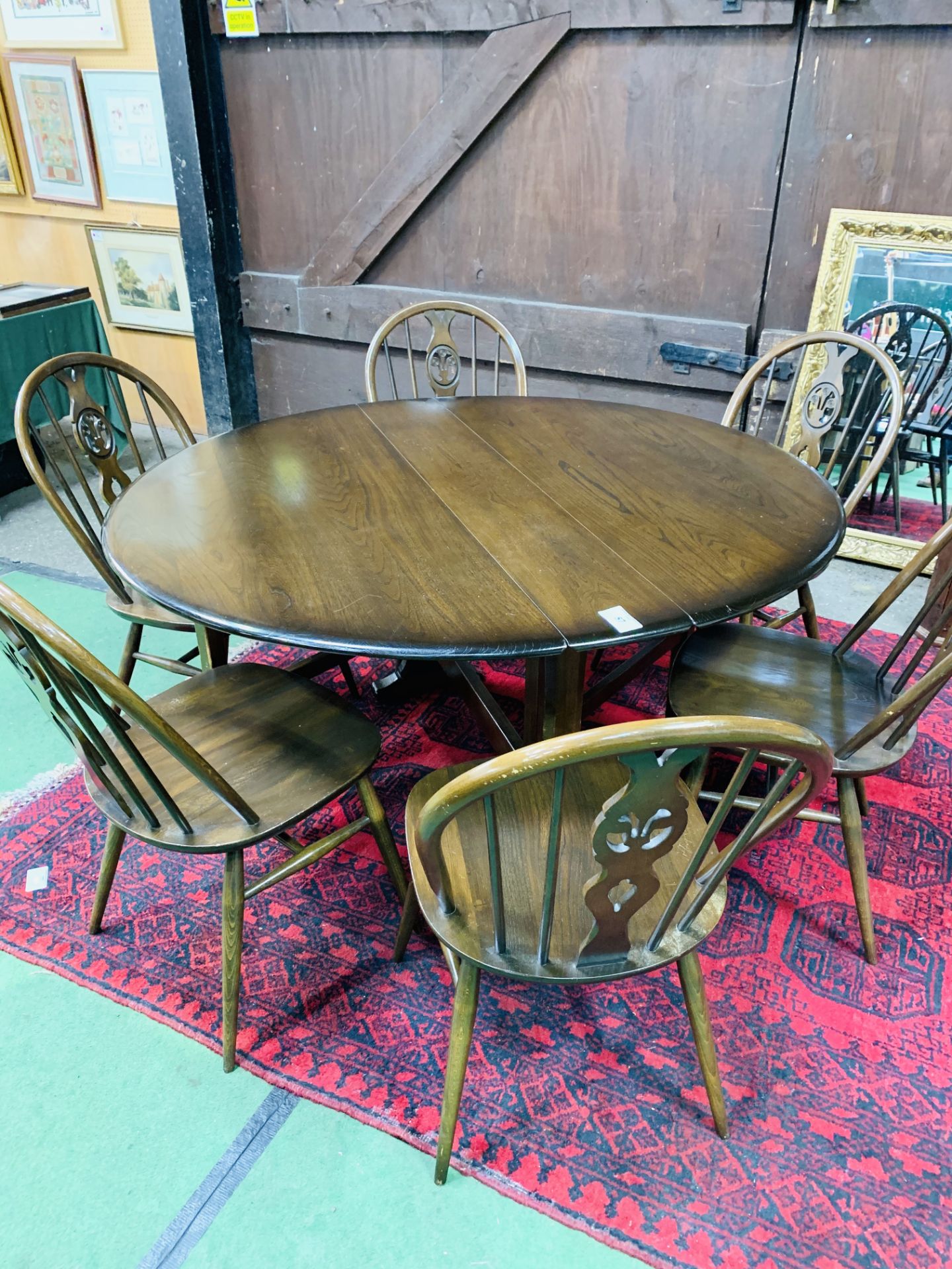 Ercol drop side dining table together with six Ercol Windsor style chairs.