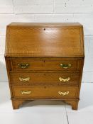 Small oak bureau with fitted interior, string inlay and brass handles, complete with key.