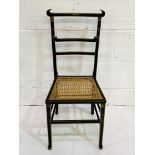 Ebonised and gilt decorated cane seat ladder back chair.