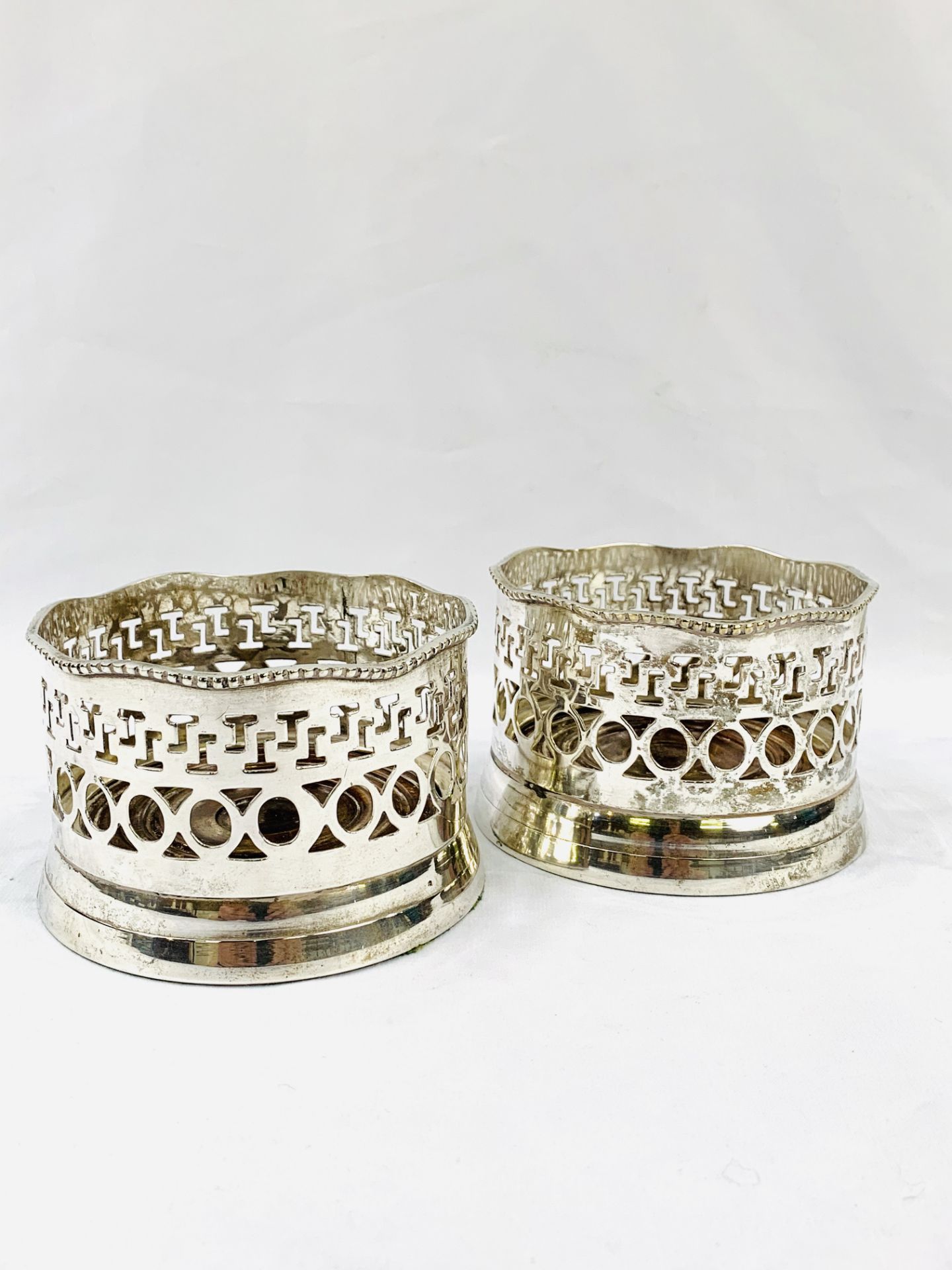 Two Victorian-style silver plate wine bottle coasters with mahogany bases.