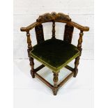 Oak framed corner chair, heavily carved, with green upholstered seat.