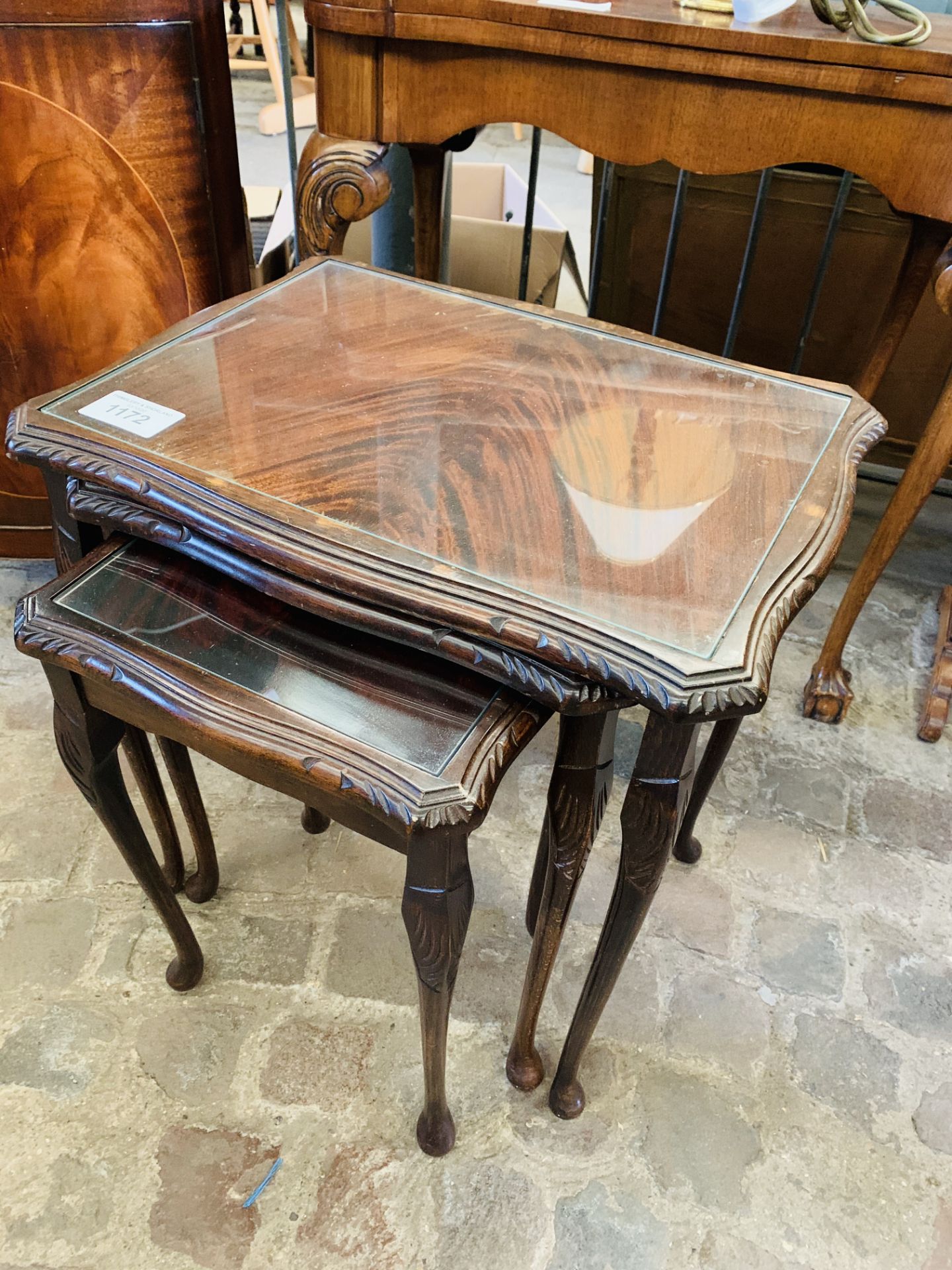 Nest of 3 mahogany tables with glass tops; together with 2 brass table lamps