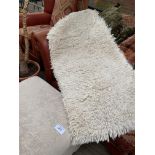 Shag pile rug and a cream upholstered ottoman