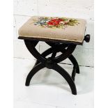 X frame adjustable height stool with tapestry upholstered seat.