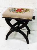 X frame adjustable height stool with tapestry upholstered seat.