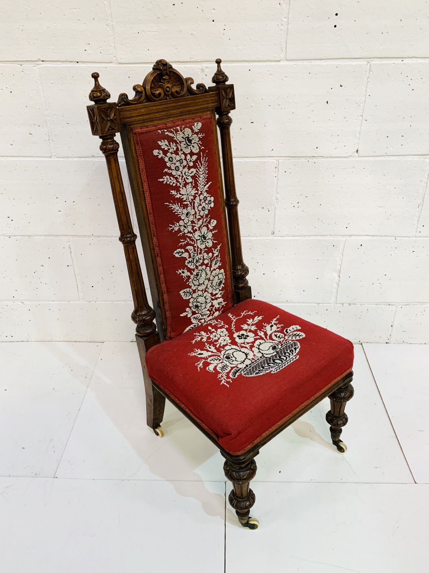 Carved mahogany framed high back hall chair with bead embroidered seat and back on ceramic casters.