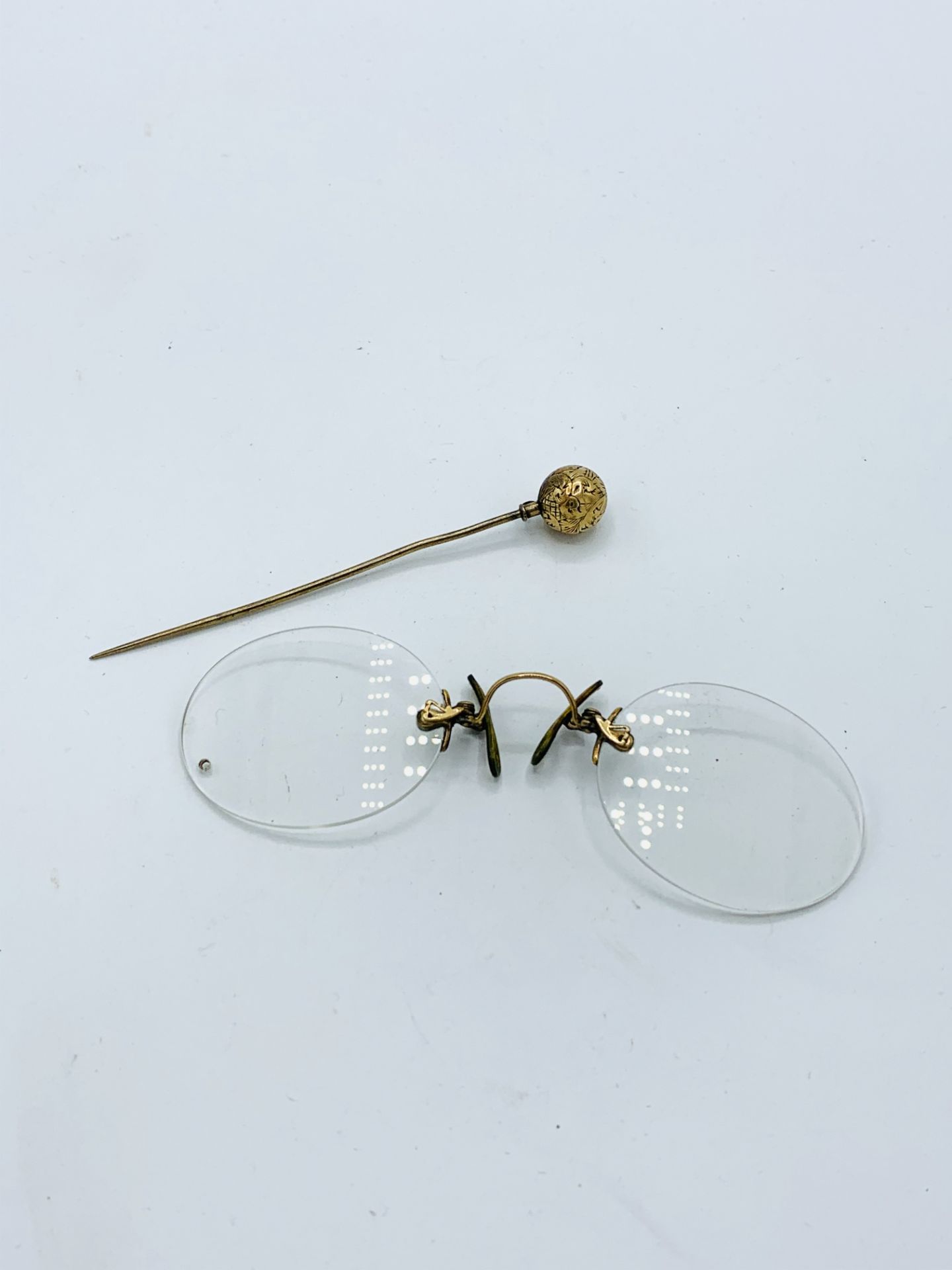 A pair of pince-nez and a gold or gold plated hat pin