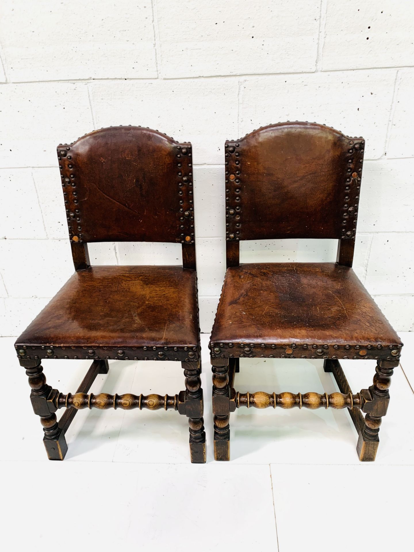 Two studded leather and oak hall chairs.