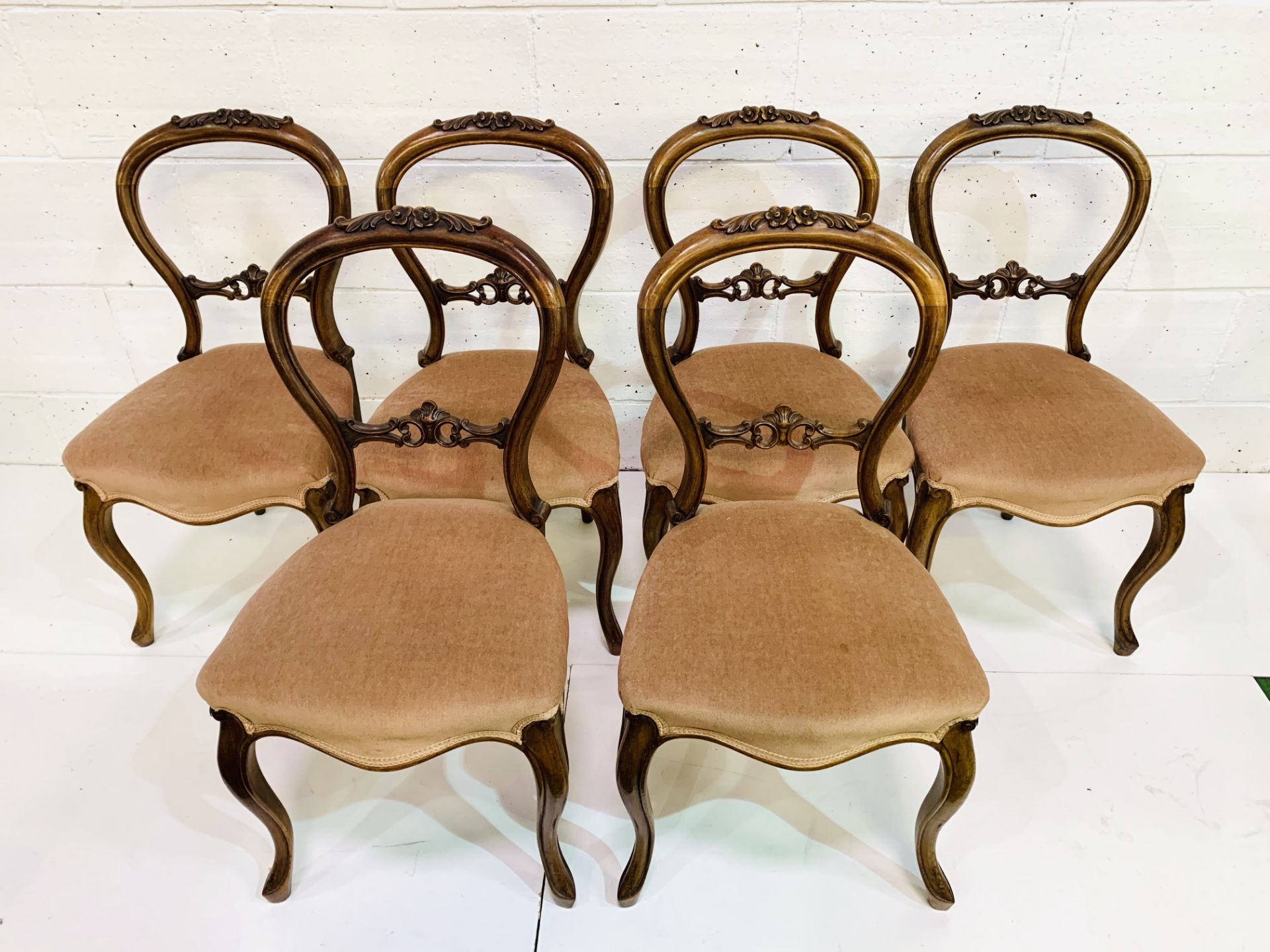 Set of six mahogany balloon back dining chairs with pink upholstered seats and carved top rail.