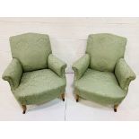 Pair of green upholstered arm chairs on ceramic casters.