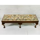 Oak framed long stool with tapestry seat depicting flowers.
