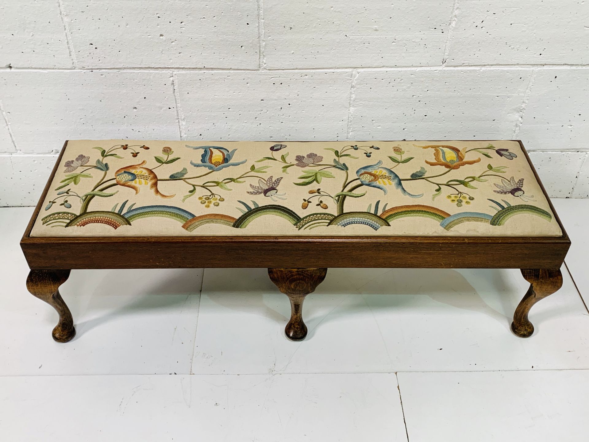 Oak framed long stool with tapestry seat depicting flowers.