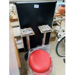 Two red plastic stools on metal bases, and a folding table.