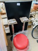 Two red plastic stools on metal bases, and a folding table.