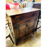 Oak cabinet with carved front and two frieze drawers.