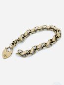 9ct gold link bracelet with padlock, requires repair.