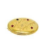 18k gold oval brooch decorated with red, blue and white stones.