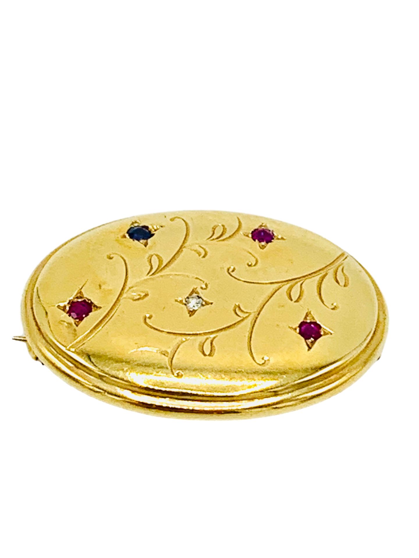 18k gold oval brooch decorated with red, blue and white stones.