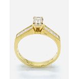 750 gold ring with baguette cut centre diamond and diamonds to shoulders.
