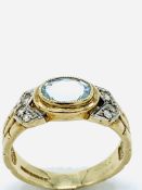 9ct gold ring set with a pale blue topaz stone and white stones on shoulders.