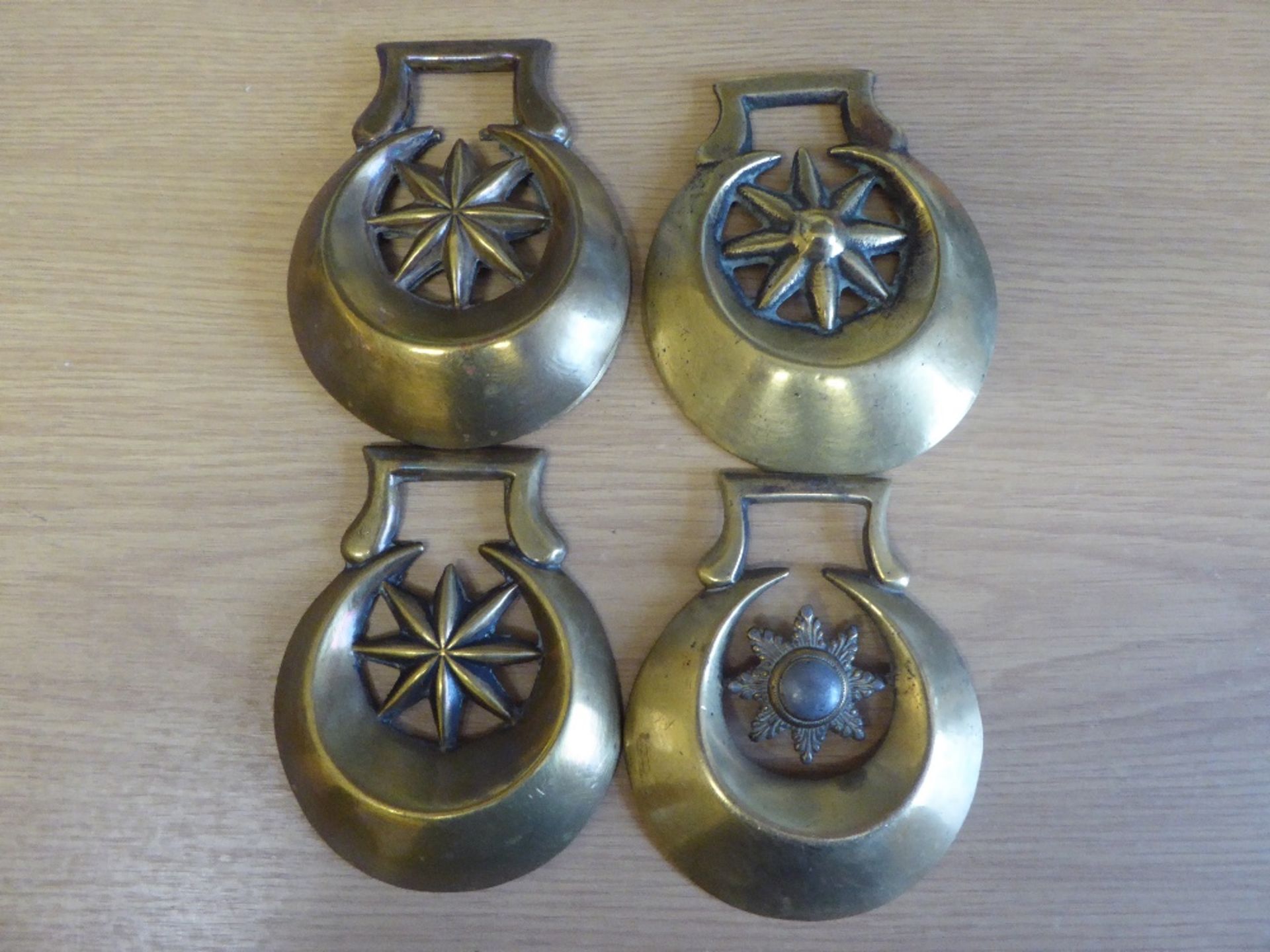 4 x stamped crescent-shaped brasses each with eight-sided centre star and 1 other crescent cast bras